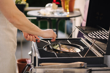Side view of male chef preparing T-bone steak on frying pan. Classic version of cocking beef. Rosemary and butter