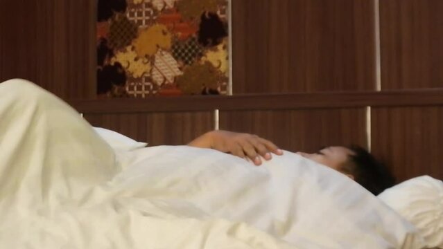 An asian man sleeps but squirms restlessly in his bed, HD video. illustration video man a lot of trouble.