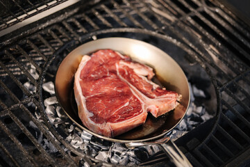 Tasty beef steak is fried in a carbon steel pan that stands on hot coals. BBQ concept