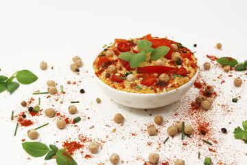 Hummus with paprika and hot pepper on a white background in a plate topped with chickpeas and sesame seeds, basil, parsley and spices. Culinary and food menu photo