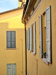 Naklejka premium Close-up of multi-colored facades of typical buildings in Modena, Emilia-Romagna, Italy - with wooden shutters and cobbled streets on a sunny spring day