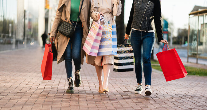 Women friends walking on city street with shopping bags after enjoying Spring sales in the mall