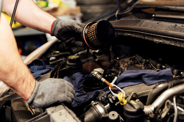 close-up of the hands of a car mechanic changing a dirty fuel filter. filter replacement in the car. car repair service. used fuel filter