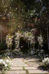 Wedding ceremony. Very beautiful and stylish wedding arch, decorated with various fresh flowers, standing in the garden. Wedding day. Fresh flowers decorations