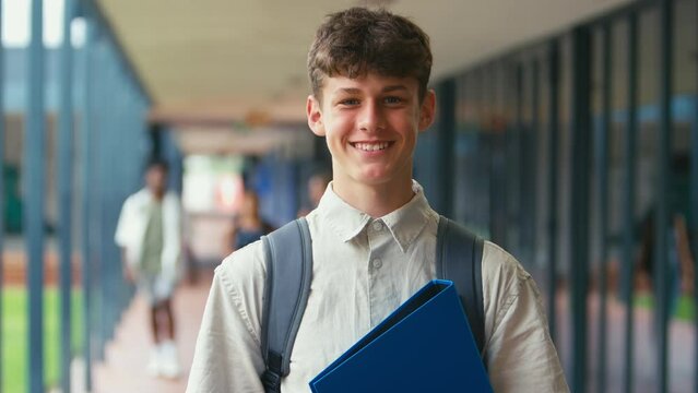 Portrait of male high school student walking outside classrooms with backpack and files - shot in slow motion