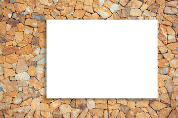 Mock up. Blank white board, billboard, advertising, public information board on brown masonry wall of stones with irregular pattern texture background. Mock up on grunge stone wall in sunny day