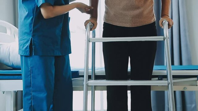 young asian physical therapist working with senior woman on walking with a walker