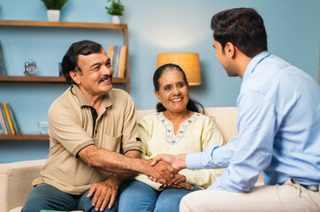Shoulder shot of banking officer greeting senior couple at home - concept of home banking service, professional occupation and investment advisor