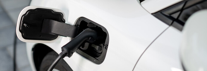 Closeup electric vehicle plugged-in with cable from charging point powered for progressive concept...
