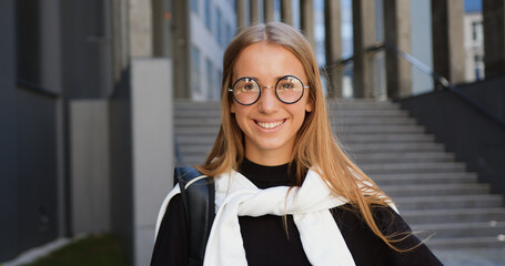 Nice cheerful lucky 25-aged light-haired stylish girl in eyeglasses looking at camera with...
