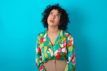 young arab woman wearing colorful shirt over blue background looking sleepy and tired, exhausted for fatigue and hangover, lazy eyes in the morning.