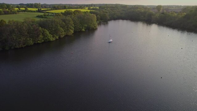 Push in aerial footage of Wroxham Broad, a body of water in the heart of the Norfolk Broads National Park. Captured on a bright summer evening just before the sun started to set