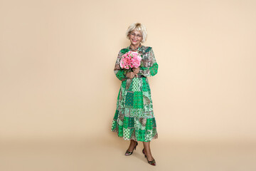 Happy mother's day! Beautiful happy senior woman in elegant floral dress is holding bouquet of...