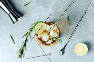 Alcohol cocktail with lime slice rosemary ice and cocktail jigger on black background. Party time