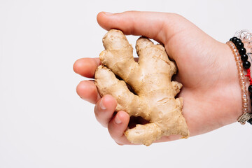 Close up of a ginger root being held in hand and against a white background.