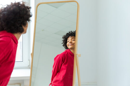Love yourself. Beautiful young smiling african american woman dancing enjoying her mirror reflection. Black lady looking at mirror looking confident and happy. Self love concept