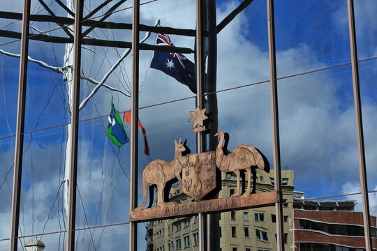 Glass wall of the Australian National Maritime Museum harborside entrance reflecting flags-sky-buildings. Sydney-Australia-620