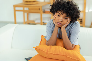 African american sad thoughtful pensive unmotivated girl sitting on sofa at home indoor. Young...
