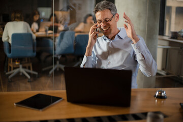 Fototapeta na wymiar Businessman in office. Handsome man talking on phone at work.