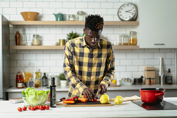 African man preparing food in modern kitchen. Handsome chef cooking pasta.