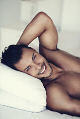 Portrait, happy and morning with a sexy man in bed, shirtless after a rest to relax while ready to wake up. Face, smile and body with a handsome or sensual young male model lying topless in a bedroom