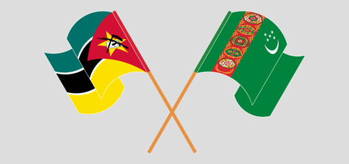 Crossed and waving flags of Mozambique and Turkmenistan