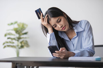 Unhappy young asian woman sit at home use cellphone have problems shopping online with credit card....