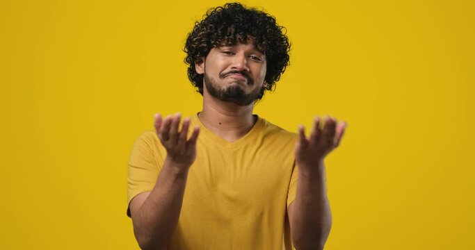 Grateful thankful appreciative young indian man holding hands near chest touching heart isolated on orange studio background
