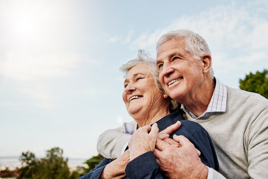Sky, elderly couple and hug outdoors or happy in retirement or husband and wife in nature. Mature, man and woman smile in vacation or senior citizens care and embrace or date at the park for romance