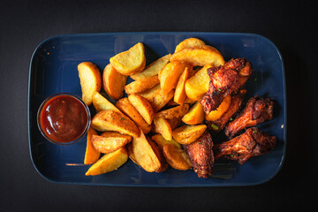 Top view - Fried crispy chicken wings with spicy potato wedges- black background
