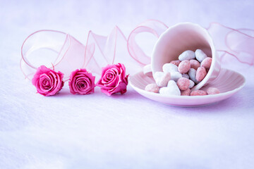 ピンクのプリザーブドフラワーフラワーのバラとコーヒーカップに入れたアーモンドドラジェとリボン
