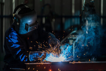 A labor wearing industrial uniforms and welded iron mask at steel welding plants.Industrial safety first concept.
