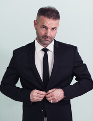 Used to success. Confident young businessman adjusting his jacket and looking away while standing against grey background. 