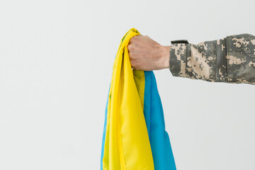 The Ukrainian military man holds the flag of Ukraine in his hands. War, conflict, Ukraine