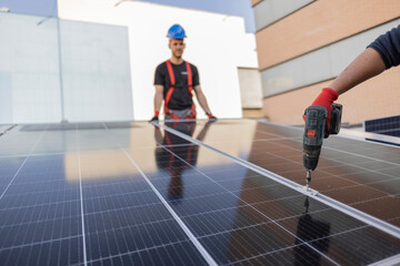 Men technicians carrying photovoltaic solar moduls on roof of house. Builders in helmets installing solar panel system outdoors. Concept of alternative and renewable energy. © PintoArt