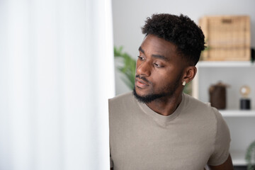 African american young man looking through window.