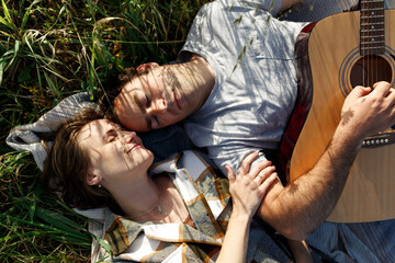 Happy couple in love on a romantic date at the park on a picnic. Playing on a guitar and having fun...