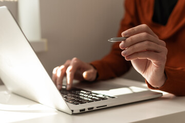 Businessman hand holding pen working on laptop computer, working online concept, e business concept