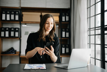 Confident business expert attractive smiling young woman typing laptop ang holding digital tablet on desk in creative office..