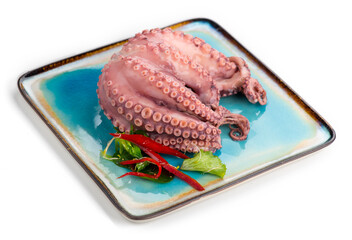 Octopus serving with vegetables, sea food. Freshly boiled octopus on a blue plate, Mediterranean...