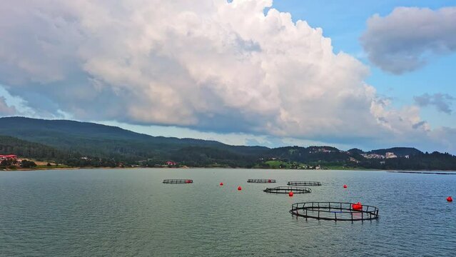 Fishing cages for breeding fish in lake in mountain valley of Rhodope Mountains under cloudy sky