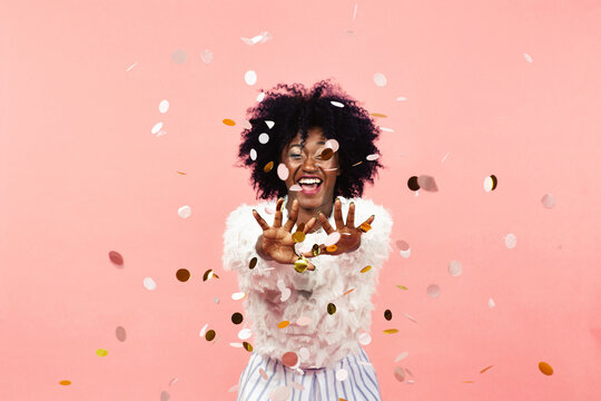 Celebrating happiness, young woman with big smile throwing confetti