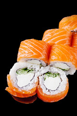 sushi roll with salmon cream cheese philadelphia cucumber on a black mirror background