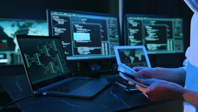 With currency in hands. Young professional female hacker is indoors by computer.