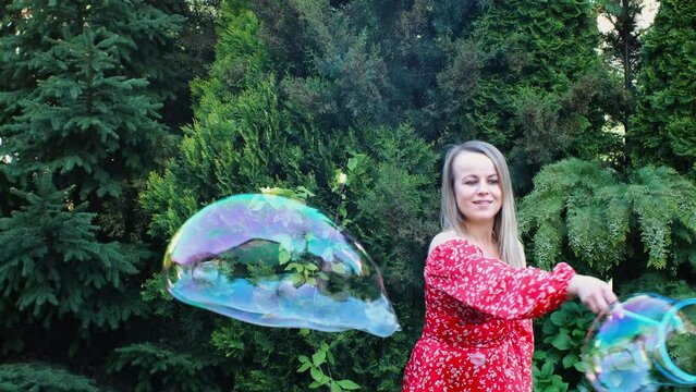 a woman in a red dress is playing with soap bubbles on the green lawn
