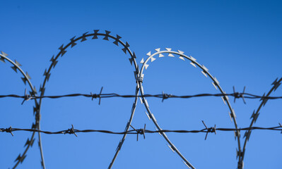 Barbed wire protection fence. Concept photo for security and lack of freedom. Blue sky background.