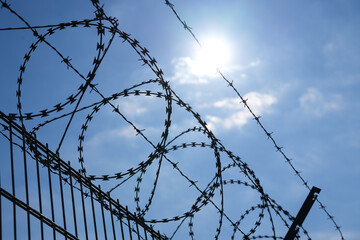 Barbed wire protection fence. Concept photo for security and lack of freedom. Blue sky background.