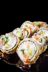 hot sushi roll tempura with salmon cream cheese cucumber avocado unagi on a black mirror background