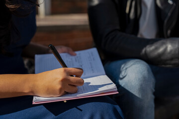 Close-up of students writing in notebook