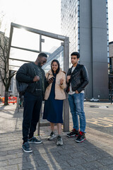 Smiling friends using phone on campus